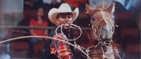 A man rides a horse with a rope in his hand during a rodeo