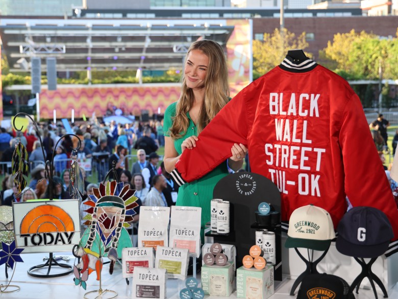 Olivia Jordan stands with a table full of merchandise from local brands.