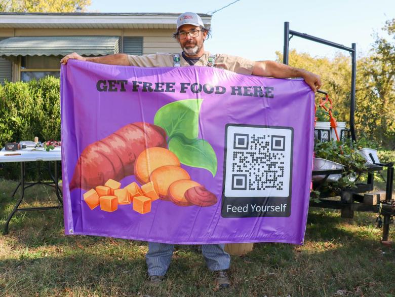 Matthew Woodson, a nurse and founder of Front Yard Farms, holds a banner advertising free food in Tulsa Nov. 5, 2025. He grows sweet potatoes and hopes others also learn to sustain themselves, especially after the pause in food benefits revealed how fragile the food system is.