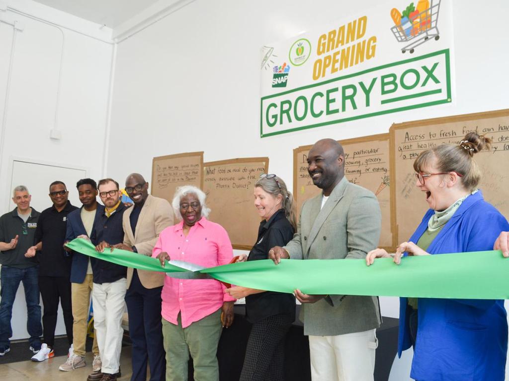 Katie Plohocky, executive director of RG Foods cuts a ribbon celebrating the opening of the Grocery Box, a micro grocery store and deli at the Phoenix 36N Apartments.