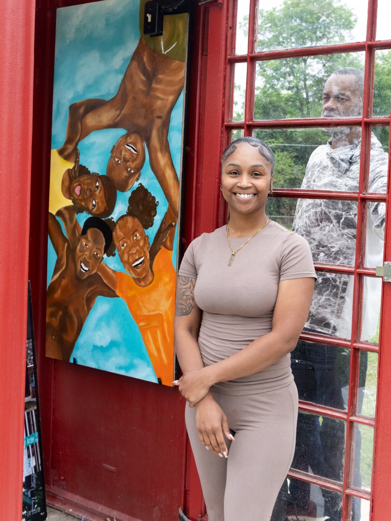 Artist Anecia Fowlkes stands next to her new art display inside a phone booth next to Stutts House of Barbeque unveiled on April 16, 2026.
