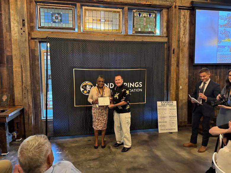 Betty Towns (Jackson), left, and Bob Lemons accept a Sandite Hall of Fame plaque honoring the nine students who desegregated Charles Page High School in Sand Springs at an April 16, 2026, event.