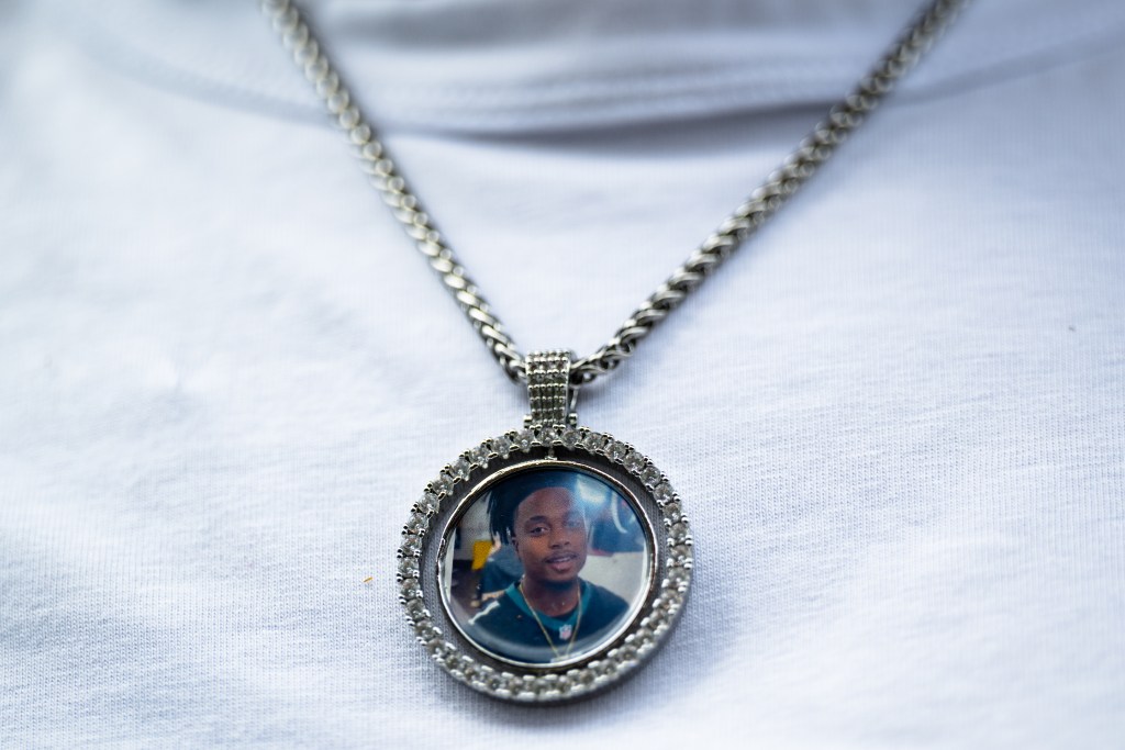 Angel Spears wears a necklace with a photo of her son, Isaiah Knight, near his memorial in Greenwood April 29, 2026. She described Knight as "very kind-hearted and respectful."