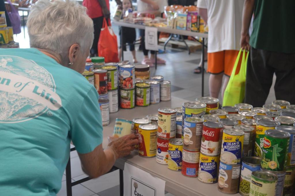 A woman picks up a can of food at the Stored Goodness Community Market at the O'Brien Park Recreation Center on June 26, 2026.