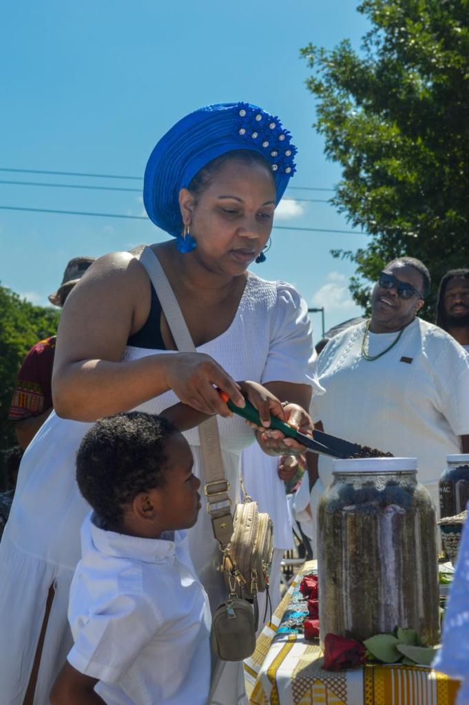 A woman and child pour soil into a jar at a May 31, 2026, ceremony honoring victims and survivors of the 1921 Race Massacre.